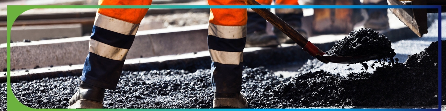 Construction worker shoveling pavement mix