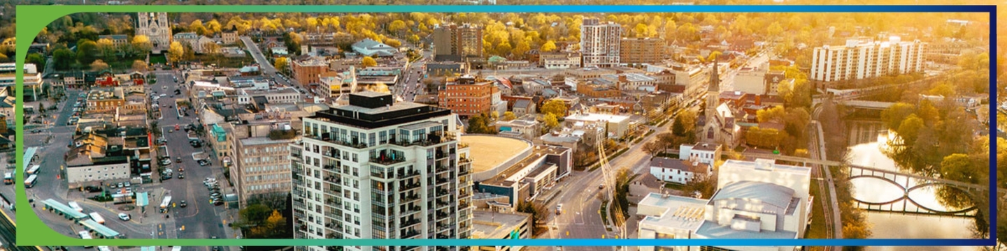 View of City of Guelph from aerial view of downtown, buildings and river with bridge. Sun setting in the background..