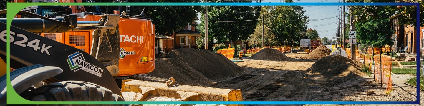 A street under construction with a backhoe in the foreground