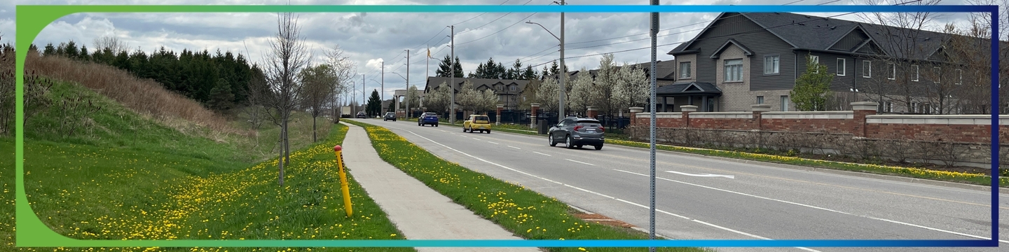 Guelph street near Gordon and Clair with sidewalk, grassy area with dandelions, brick wall separating houses, cars on the road, and overcast sky with power lines overhead.