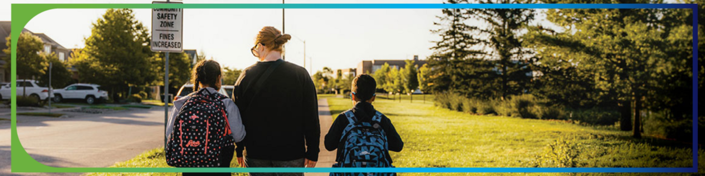 adult and children walking on sidewalk to or from school with backpacks on