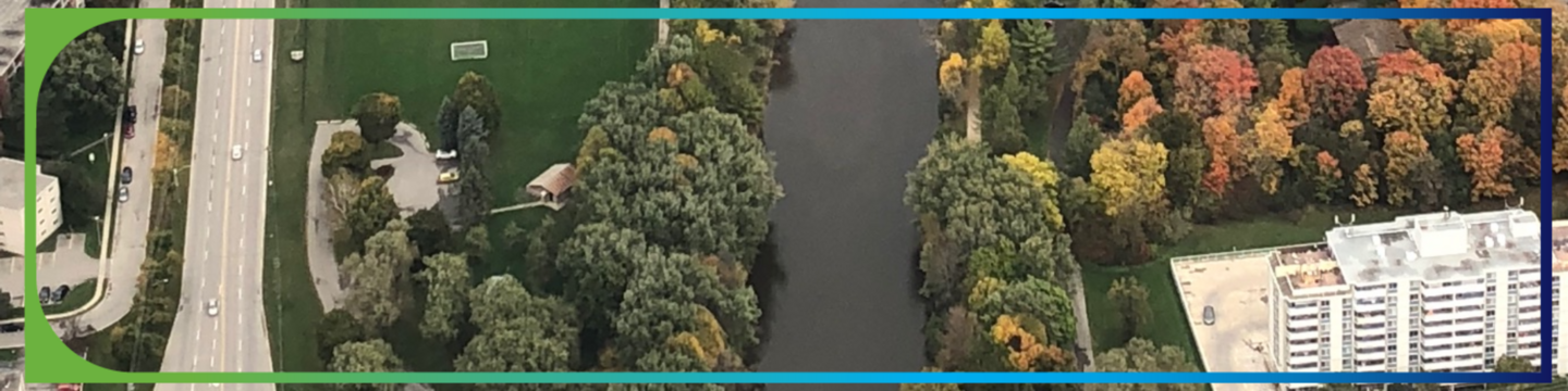 Aerial view of town overlooking trees, roads, river and buildings. 