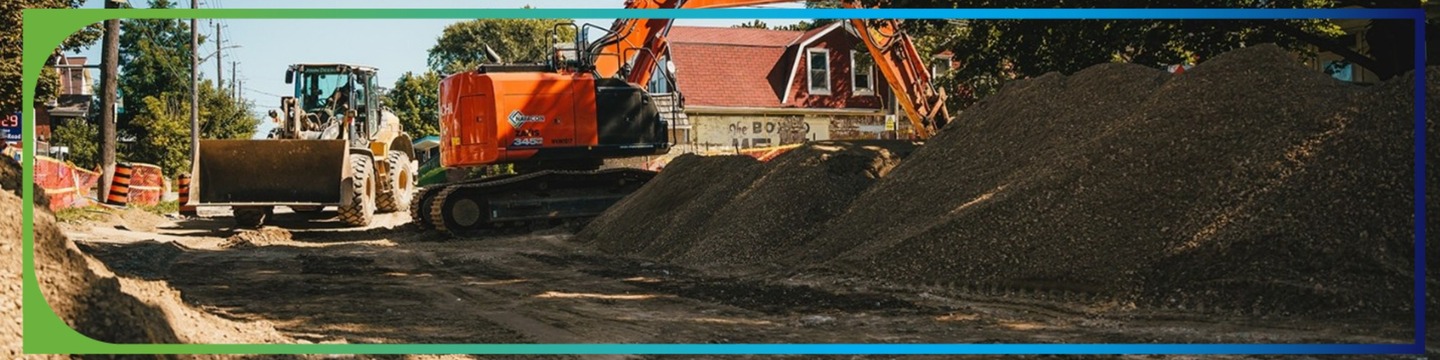 Photo of a road under reconstruction with an excavator and digger in the background