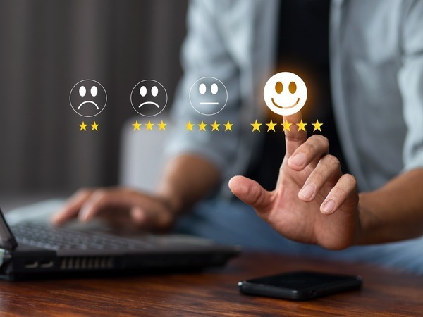 A person at a computer selects a a smiley face with 5 stars on a scale of two stars and a frowny face to 5 stars and a smiley face. 